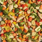 Delicious Sheet Pan Chicken with rainbow vegetables, baked with lemon and parmesan.