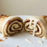 Tortilla cinnamon roll cut in half showing gooey cream cheese and cinnamon sugar swirls